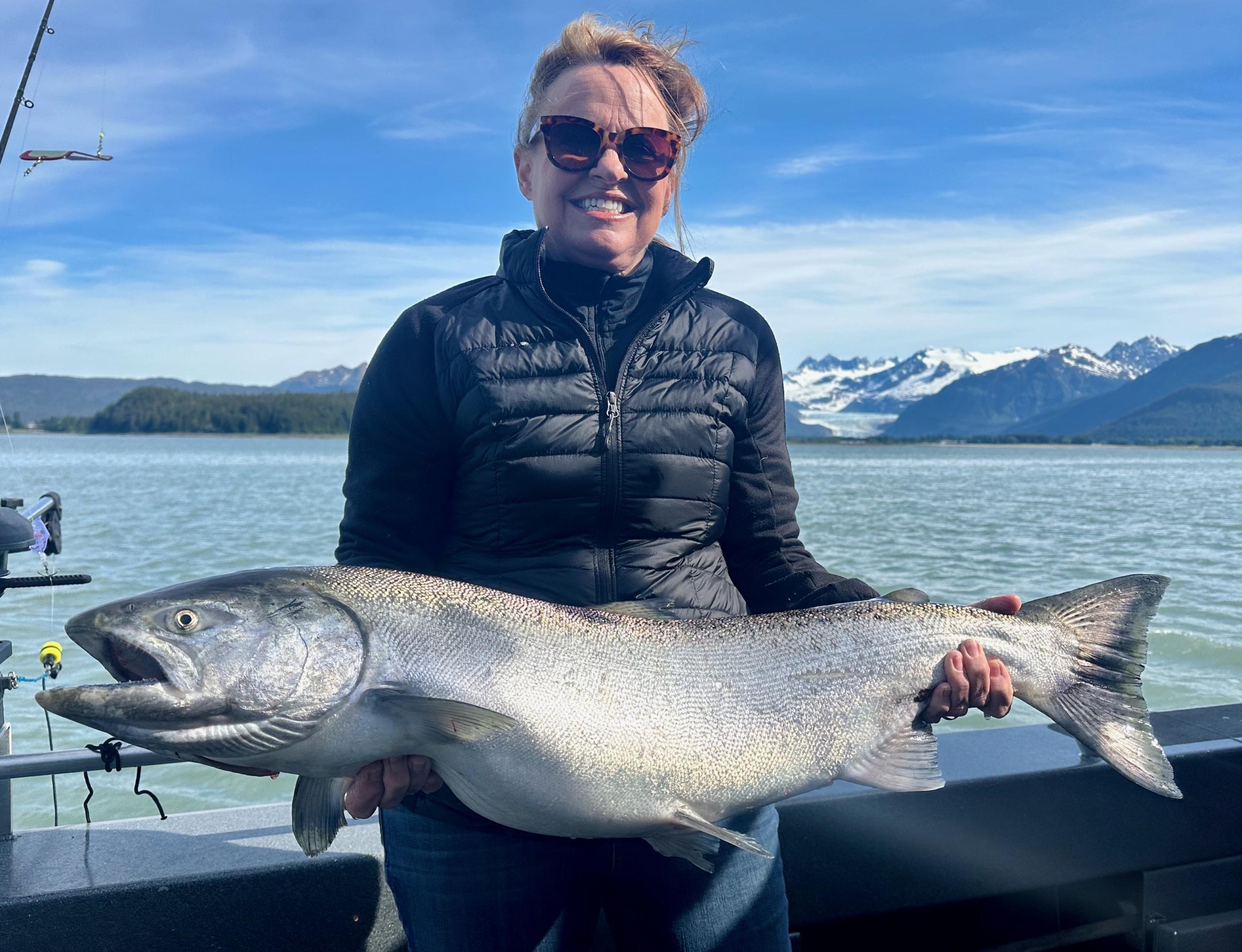 An angler holding a freshly caught king salmon on a fishing charter in Juneau, Alaska.